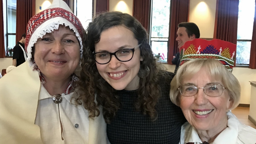 Nora Isktena (left), Liina-Ly Roos (center), and Vaira Pelekis (right) at the Latvian Cultural Center in Seattle in 2018. Nora and Vaira wear Latvian national costumes for the 100th anniversary of Latvia’s declaration of independence.