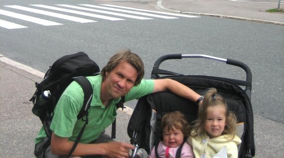 Professor Andrew Nestingen poses on a street corner in Finland with his two children in a stroller.
