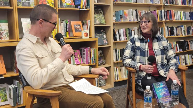 Andrew Nesting and Margaret Willson converse in chairs staged in the book store.