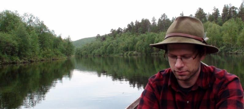 Tim Frandy paddles a canoe on a lake in the woods.