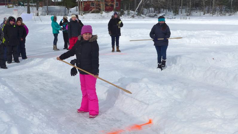 Middle school students prepare to throw snowsnakes on a frozen lake.