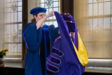 Dr. Amanda Doxtater giving the doctoral hood to a PhD graduate