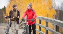 a man and a woman walking on a bridge with their bicycles