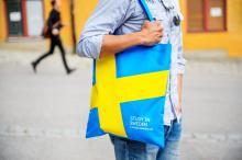 University man walking with bag, bag emblazoned with Swedish flag