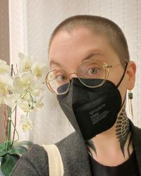 a portrait of Maxine Savage from the shoulders up wearing a black face mask and glasses