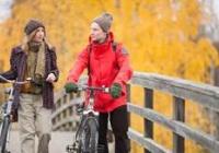 a man and a woman walking on a bridge with their bicycles